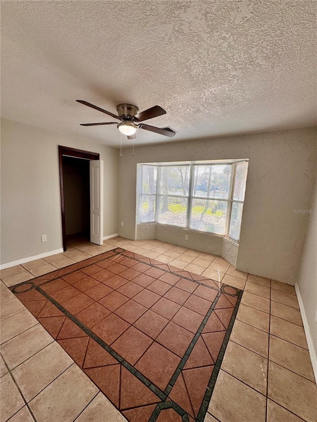 empty room with tile patterned flooring, a textured ceiling, and ceiling fan