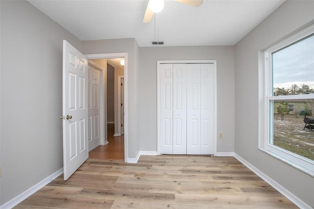 unfurnished bedroom with multiple windows, a closet, ceiling fan, and light hardwood / wood-style floors