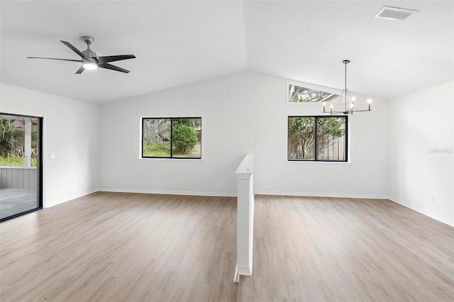 unfurnished living room featuring lofted ceiling, ceiling fan with notable chandelier, light wood-type flooring, and plenty of natural light