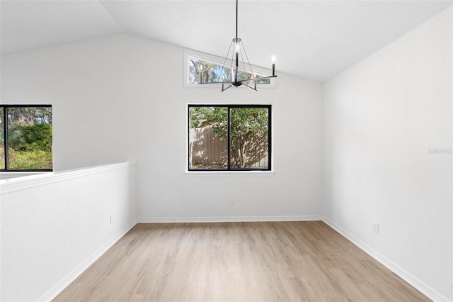 unfurnished dining area with lofted ceiling, a notable chandelier, and light hardwood / wood-style flooring