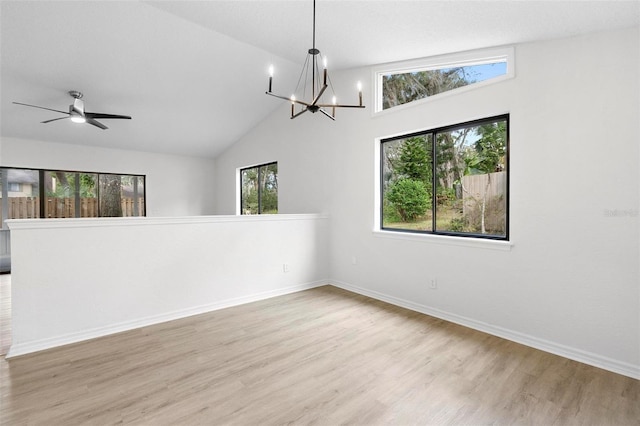 empty room featuring ceiling fan with notable chandelier, light wood-type flooring, and vaulted ceiling