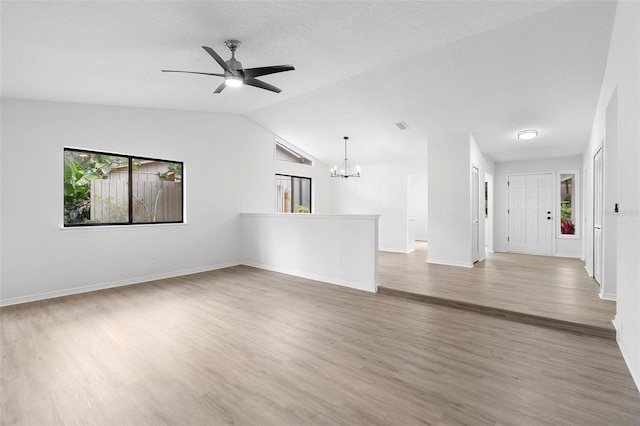 unfurnished living room featuring hardwood / wood-style floors, vaulted ceiling, and ceiling fan with notable chandelier