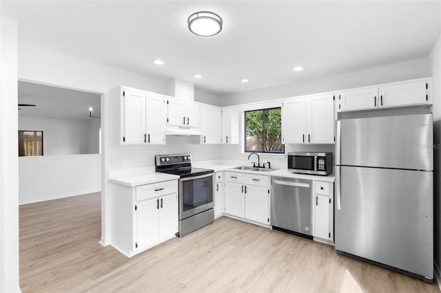 kitchen with stainless steel appliances, white cabinets, sink, and light hardwood / wood-style flooring