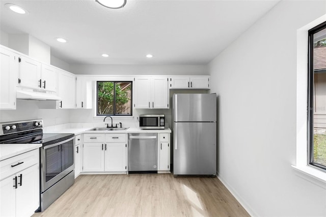 kitchen featuring stainless steel appliances, white cabinetry, sink, and a wealth of natural light