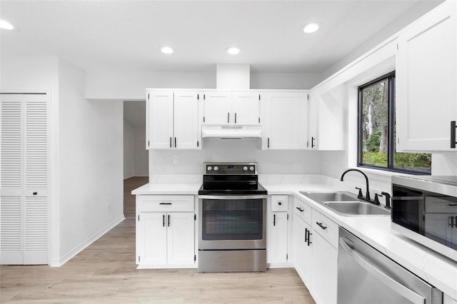 kitchen with sink, white cabinetry, light hardwood / wood-style floors, and appliances with stainless steel finishes