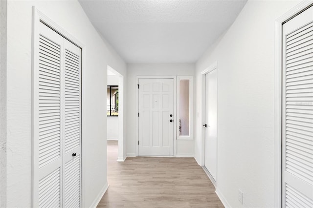 hall featuring a textured ceiling and light hardwood / wood-style floors