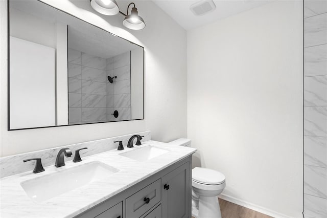 bathroom featuring toilet, vanity, tiled shower, and hardwood / wood-style floors