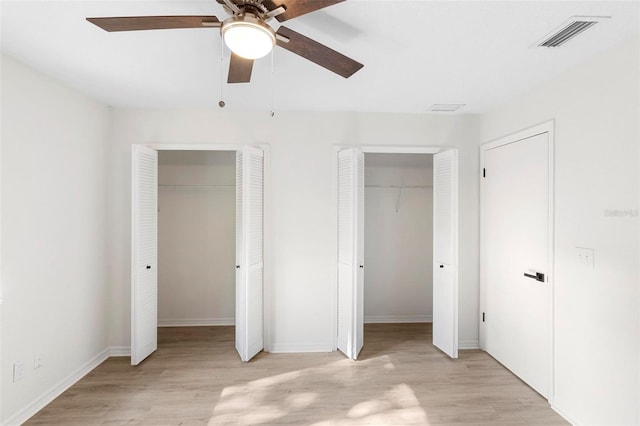 unfurnished bedroom featuring multiple closets, ceiling fan, and light wood-type flooring