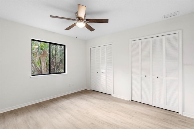 unfurnished bedroom with multiple closets, ceiling fan, and light wood-type flooring