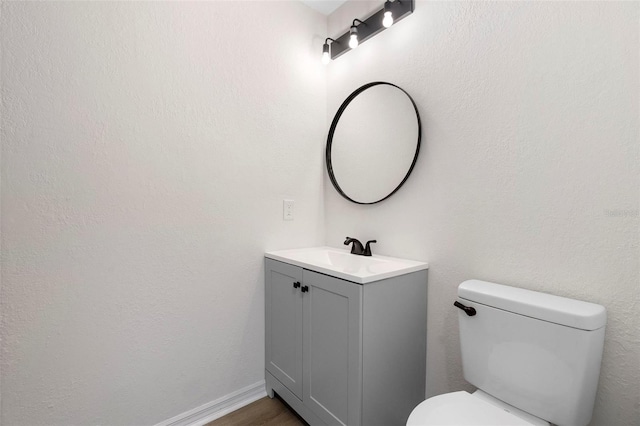 bathroom with hardwood / wood-style floors, vanity, and toilet