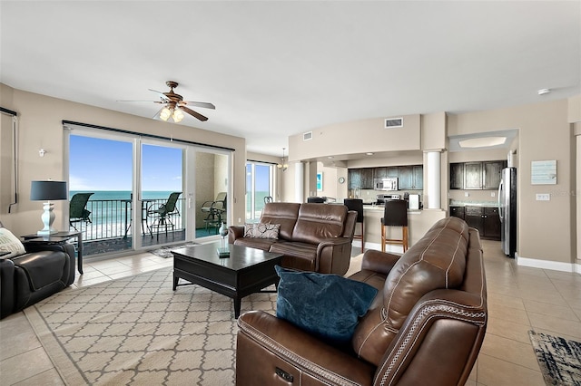 living room with ceiling fan, light tile patterned floors, and a water view