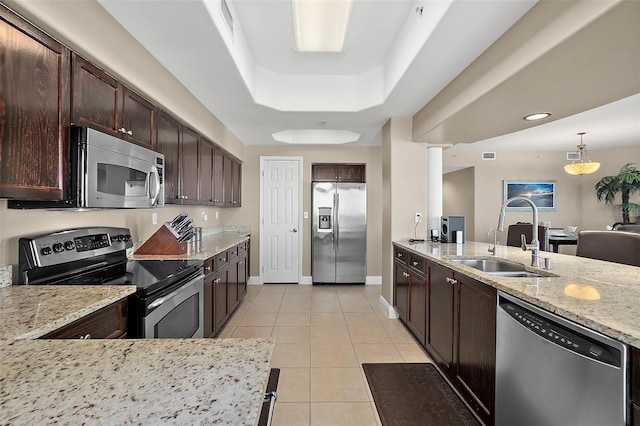 kitchen featuring light stone countertops, stainless steel appliances, sink, a raised ceiling, and light tile patterned floors