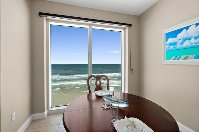 dining room featuring light tile patterned floors, a water view, and a view of the beach