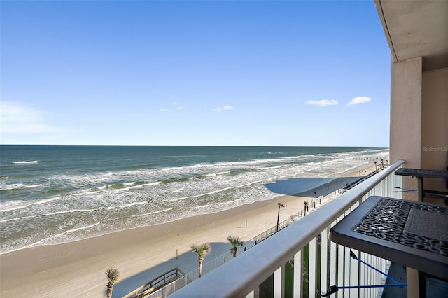 balcony with a water view and a view of the beach