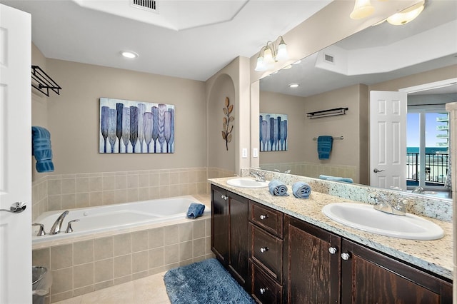 bathroom with tiled bath, vanity, and tile patterned flooring