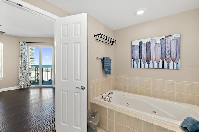 bathroom featuring wood-type flooring and tiled tub