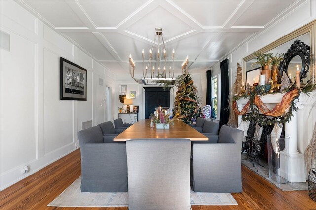 dining area with hardwood / wood-style flooring, coffered ceiling, and an inviting chandelier