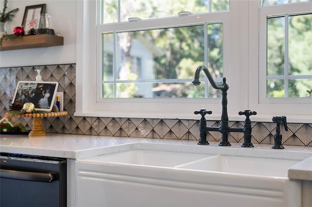 kitchen with light stone countertops, sink, a wealth of natural light, and black dishwasher