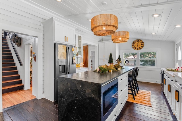 kitchen with white cabinetry, a center island, black microwave, wooden ceiling, and stainless steel fridge