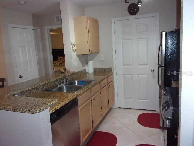 kitchen featuring stainless steel appliances, light brown cabinetry, sink, kitchen peninsula, and light tile patterned flooring