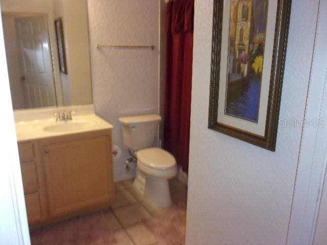 bathroom with toilet, vanity, and tile patterned floors