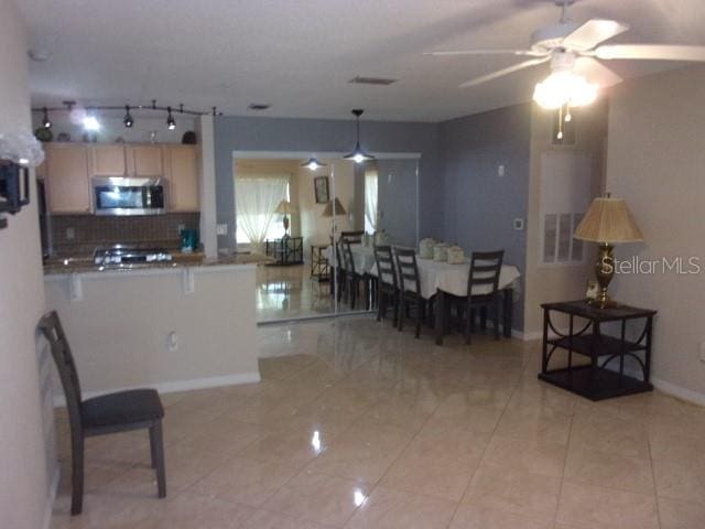 kitchen featuring light brown cabinets, backsplash, kitchen peninsula, ceiling fan, and light tile patterned floors