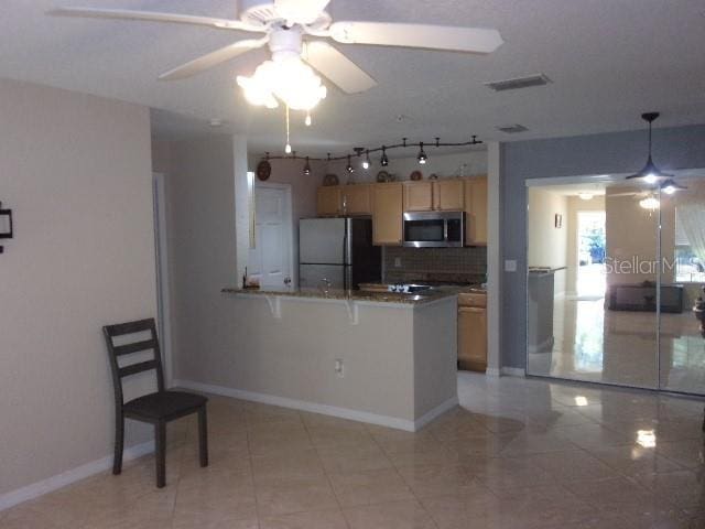 kitchen with kitchen peninsula, black refrigerator, ceiling fan, backsplash, and a breakfast bar