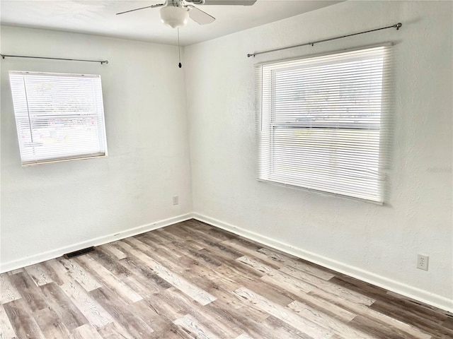 unfurnished room with ceiling fan, plenty of natural light, and hardwood / wood-style flooring