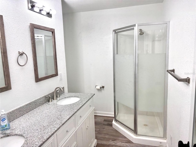 bathroom with wood-type flooring, vanity, and a shower with door