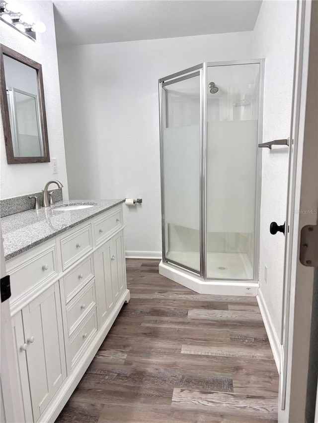 bathroom with hardwood / wood-style floors, walk in shower, and vanity