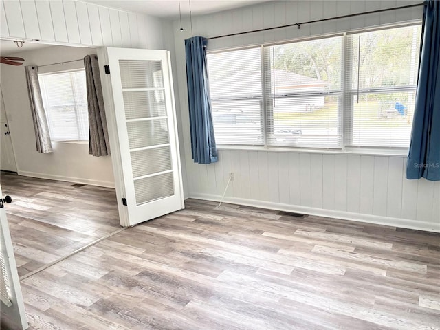 unfurnished dining area with light hardwood / wood-style flooring and wood walls