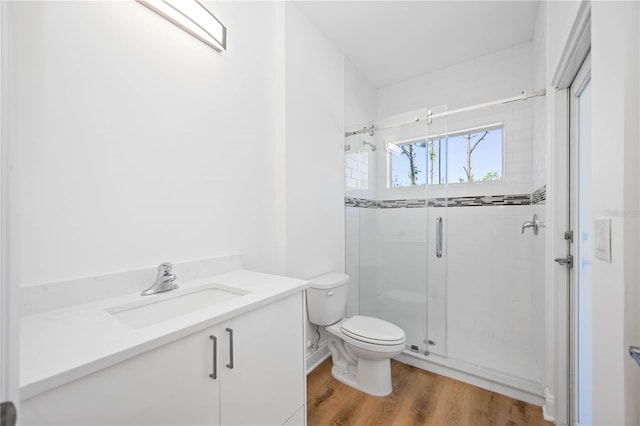 bathroom with hardwood / wood-style flooring, walk in shower, vanity, and toilet