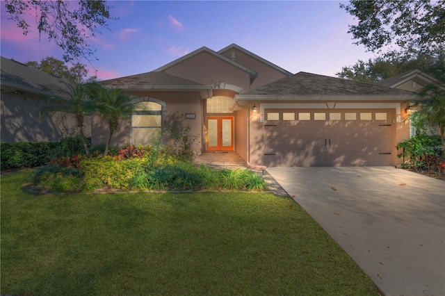 view of front facade with a garage, a lawn, and french doors