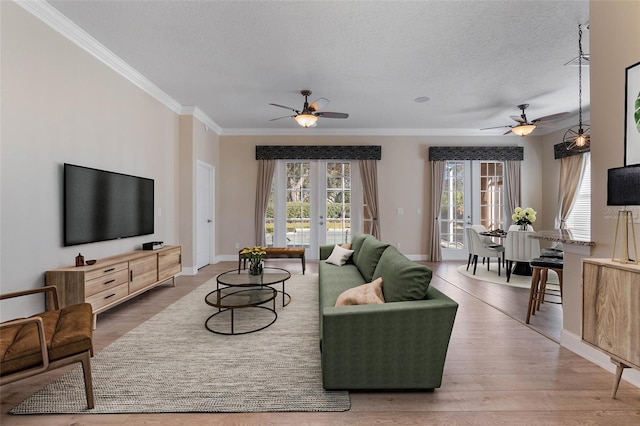 living room featuring wood-type flooring, a textured ceiling, crown molding, and ceiling fan