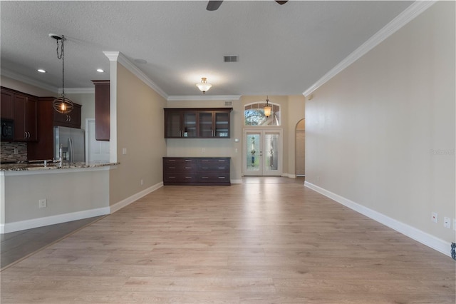 unfurnished living room with light hardwood / wood-style floors, french doors, a textured ceiling, crown molding, and sink