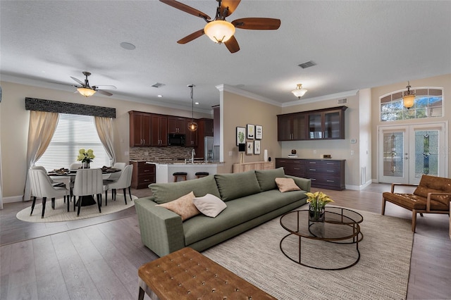 living room with ceiling fan, light wood-type flooring, a textured ceiling, crown molding, and sink