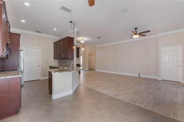 kitchen featuring pendant lighting, ceiling fan, kitchen peninsula, light stone counters, and crown molding