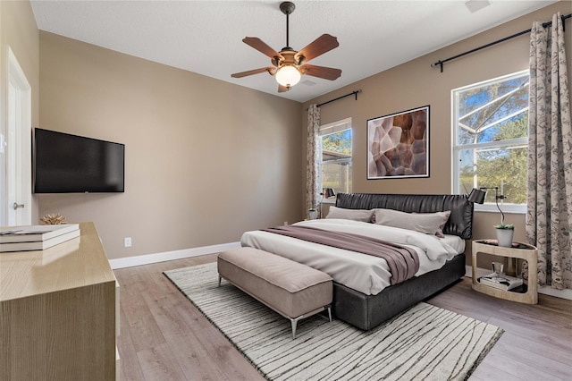 bedroom with ceiling fan, multiple windows, and light wood-type flooring