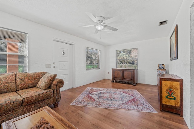 living room featuring ceiling fan, a textured ceiling, a healthy amount of sunlight, and light wood-type flooring