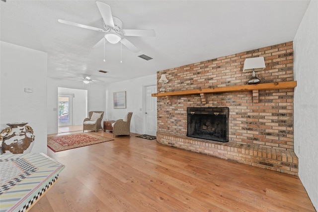 living room with wood-type flooring, a textured ceiling, and a fireplace