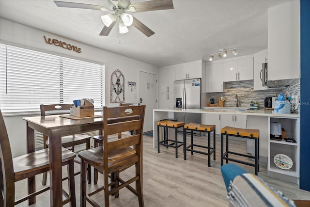 dining space with ceiling fan, light hardwood / wood-style flooring, and sink