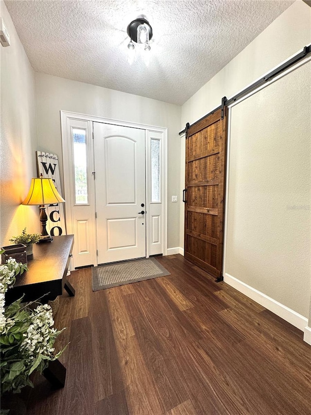 foyer with a textured ceiling, a barn door, and dark wood-type flooring