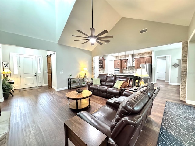 living room featuring high vaulted ceiling, ceiling fan, a barn door, and wood-type flooring