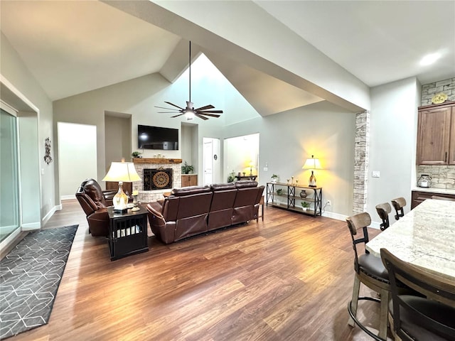 living room featuring ceiling fan, vaulted ceiling, and wood-type flooring