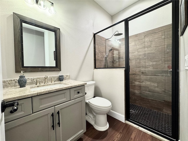 bathroom featuring toilet, hardwood / wood-style flooring, a shower with door, and vanity