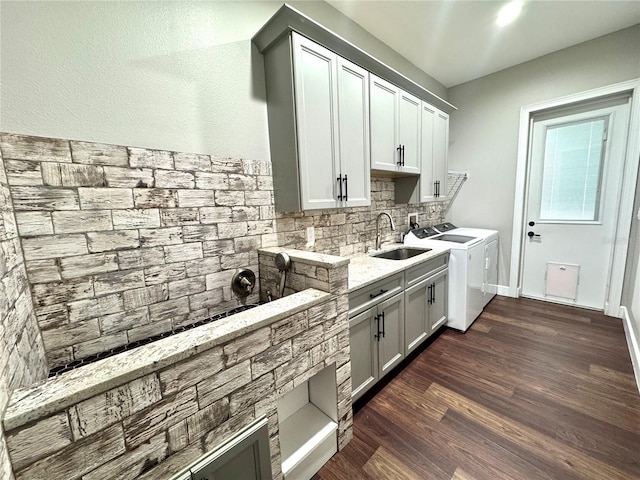 kitchen with light stone countertops, dark wood-type flooring, sink, washer and clothes dryer, and backsplash