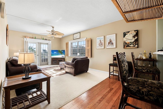 living room featuring a textured ceiling, ceiling fan, french doors, and hardwood / wood-style floors