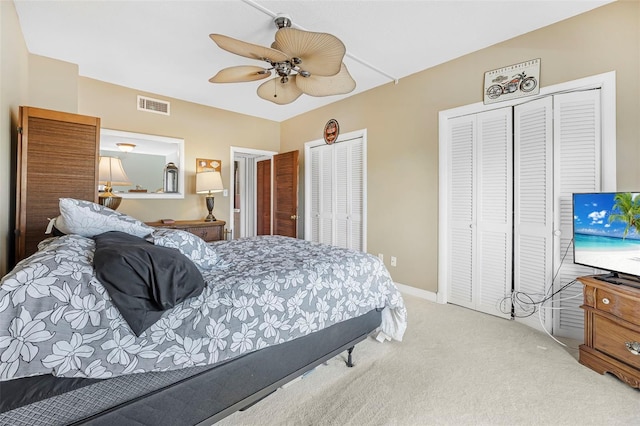 bedroom featuring light carpet, two closets, and ceiling fan