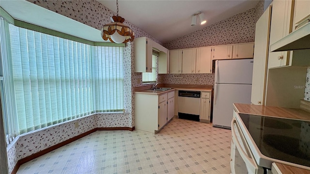 kitchen featuring sink, cream cabinetry, lofted ceiling, white appliances, and hanging light fixtures