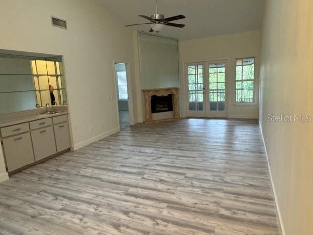 unfurnished living room with ceiling fan, light hardwood / wood-style floors, and sink